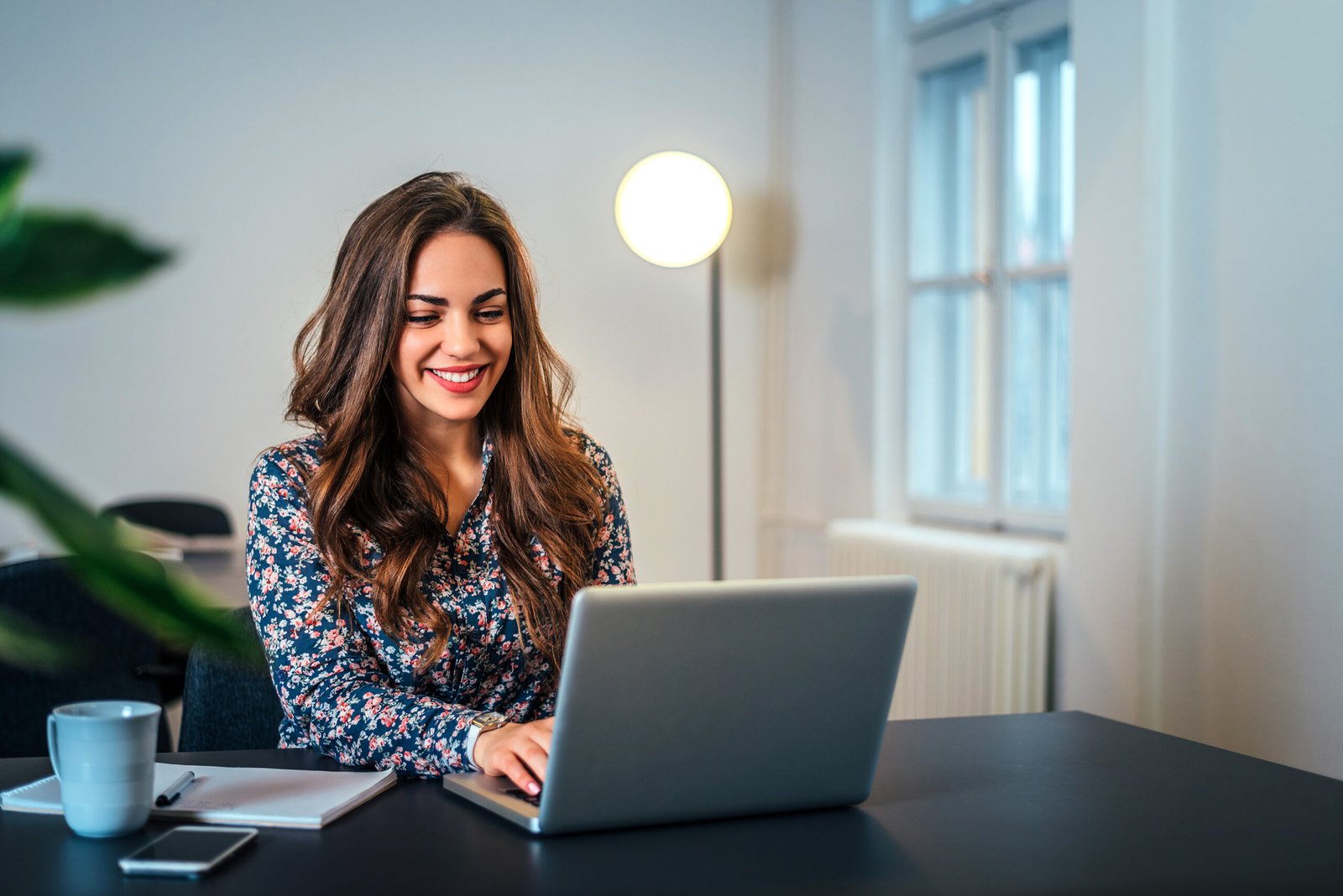 Cheerful woman using laptop at workplace.